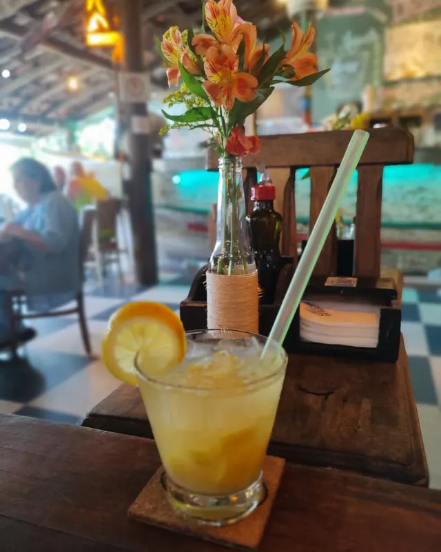 Drink com laranja na mesa, com flores ao fundo